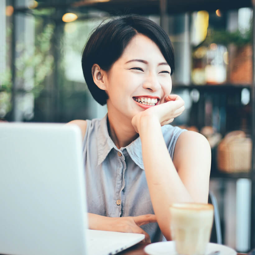 画像：パソコンをしている笑顔の女性｜株式会社アッシュゴールド